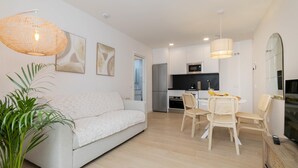 Un salon moderne avec un canapé, une table à manger, des chaises et une cuisine en arrière-plan.