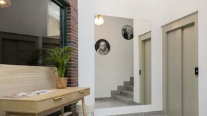 Un intérieur moderne avec un bureau en bois, une plante en pot et un escalier menant à un ascenseur.