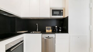 A modern kitchen with white cabinets, a black countertop, a stainless steel dishwasher, and a Bosch microwave. - Aurora Stays by Charming XI, Apartment for 4 with free parking (Madrid)