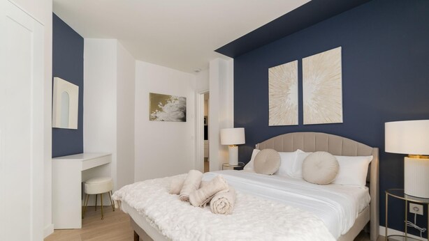 A modern bedroom with a large bed, bedside tables, a desk, and artwork on the walls. - Aurora Stays by Charming XI, Apartment for 4 with free parking (Madrid)