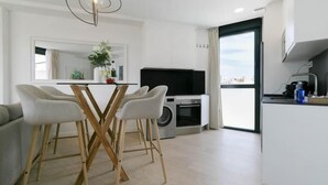 A modern kitchen with a dining area, a TV, and a view of the city.