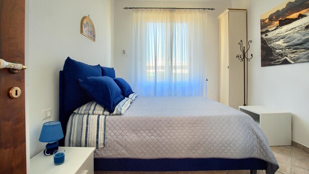 Une chambre à coucher avec un lit, une table de chevet avec une lampe, un tableau accroché au mur et une peinture.