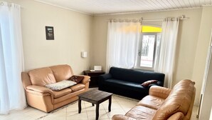 A living room with a beige sofa, a dark sofa, and a brown leather sofa. There is a small wooden table in the center. - HOUSE/21 PEOPLE/POOL/AIR/4 SPACES/BABY/BILLIARDS (Centro Balneário Camboriú)