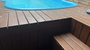A rectangular pool with a blue interior, surrounded by a wooden deck. - HOUSE/21 PEOPLE/POOL/AIR/4 SPACES/BABY/BILLIARDS (Centro Balneário Camboriú)