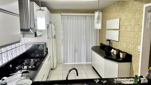 A modern kitchen with a black countertop, stainless steel sink, and a gas stove. - HOUSE/21 PEOPLE/POOL/AIR/4 SPACES/BABY/BILLIARDS (Centro Balneário Camboriú)