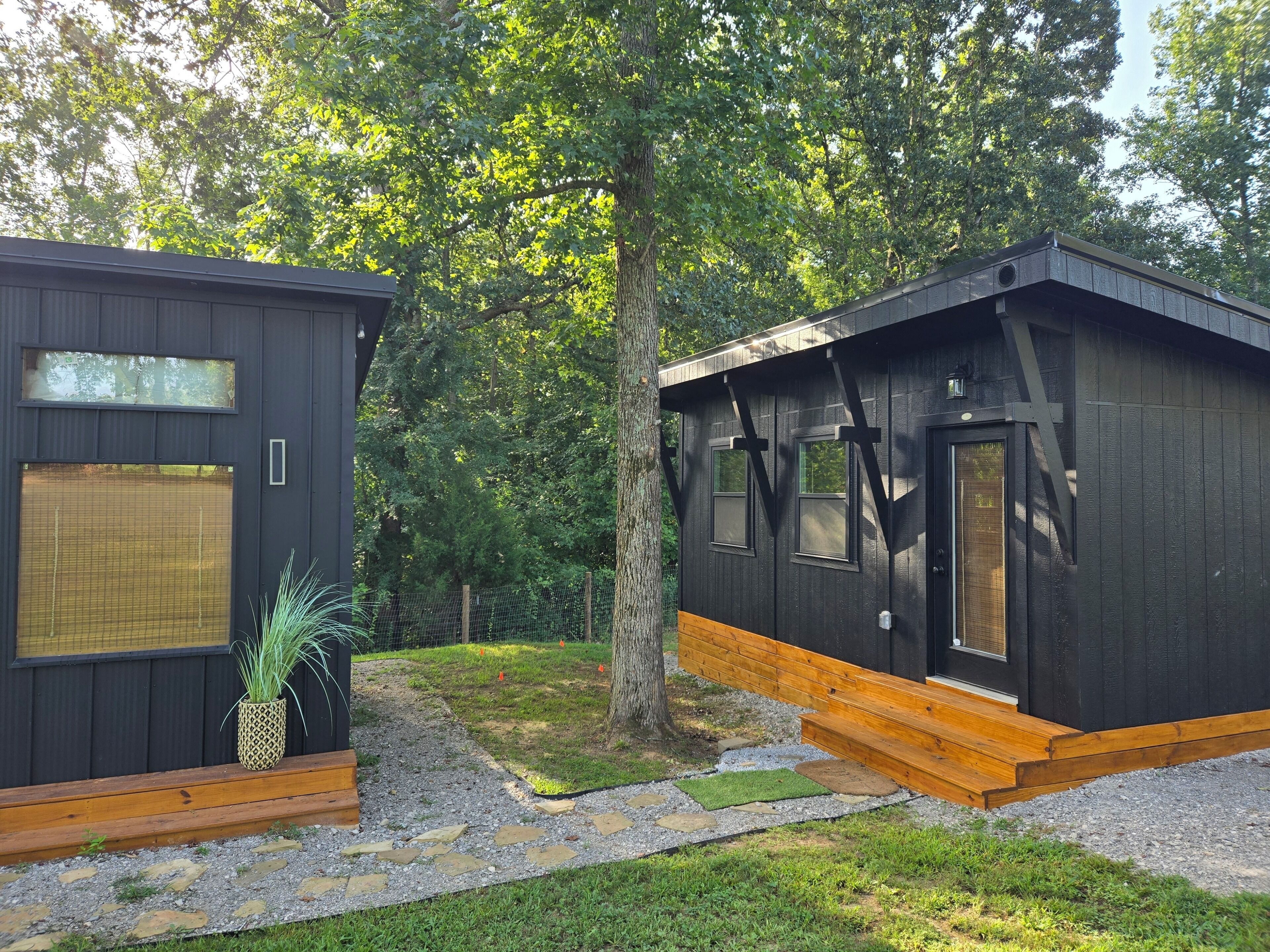 A modern cabin with a wooden deck, a small garden area, and a large window.