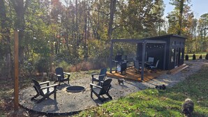 An outdoor patio with a grill, seating area, and a small covered structure. - Pet friendly fenced yard, 2 tiny homes rented as one close to Fall Creek Falls (Sparta)