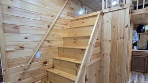 A wooden staircase leading to a lofted area with a kitchen in the background. - Pet friendly fenced yard, 2 tiny homes rented as one close to Fall Creek Falls (Sparta)
