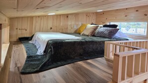 A wooden cabin bedroom with a bed, pillows, and a window. - Pet friendly fenced yard, 2 tiny homes rented as one close to Fall Creek Falls (Sparta)