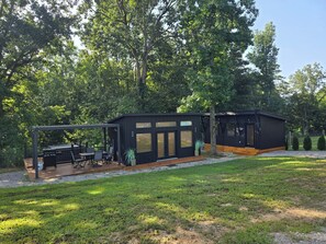 A modern outdoor kitchen area with a dining set and a pergola.
