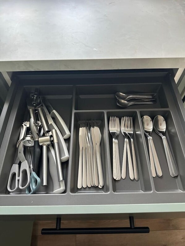 A drawer with compartments containing various kitchen utensils and tools.
