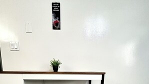 Una kitchenette pequeña y blanca, con una mesa negra y una planta en maceta sobre la encimera.