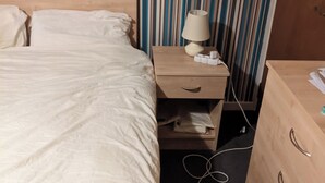 A bed with a white duvet, a wooden nightstand with a lamp, and a drawer. - Birch Cabin Retreat in Girvan (Girvan)