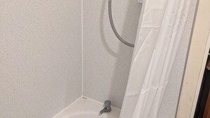 A corner of a bathroom with a bathtub, a shower hose, and a white curtain. - Birch Cabin Retreat in Girvan (Girvan)