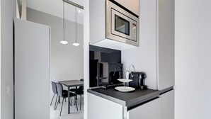 A compact kitchen with a microwave, a coffee machine, and a small dining area with chairs and a table.
