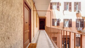 A narrow corridor with a welcome mat, a door, and a railing on one side.