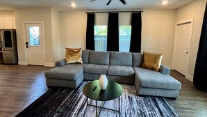 A modern living room with a sectional sofa, a green coffee table, and a ceiling fan. - Modern Houston Home 7 Min to NRG Stadium & Med Center (Houston)