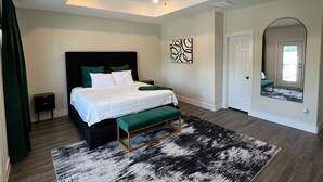 A bedroom with a bed, a bench, a ceiling fan, a door, and a wall art piece. - Modern Houston Home 7 Min to NRG Stadium & Med Center (Houston)