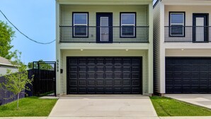 A two-story residential building with a garage and a small balcony on the upper floor. - Modern Houston Home 7 Min to NRG Stadium & Med Center (Houston)