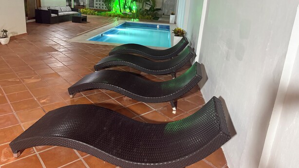 Zona junto a la piscina con sillas de descanso y una pileta.