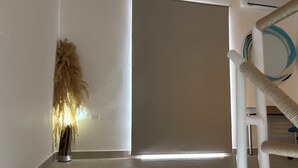 Un interior moderno con diseño minimalista, que presenta una puerta grande, una decoración mural con textura y un rascador para gatos.