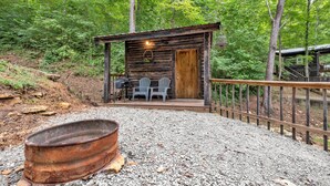 A rustic cabin with a wooden exterior, a porch with two chairs, and a gravel pathway leading to it.