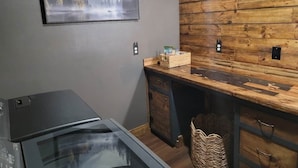 A modern kitchen with a wooden wall, a refrigerator, a microwave, and a basket on the counter.
