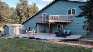 A two-story house with a deck, outdoor seating, and a small shed.