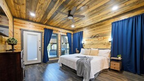 A wooden-paneled bedroom with a bed, nightstand, and a ceiling fan.