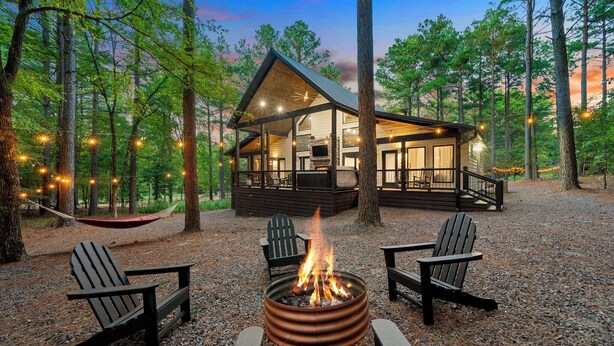 Een chalet met terras, vuurkuil en Adirondack-stoelen.