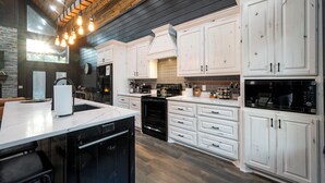 Een moderne keuken met witte kasten, een centraal eiland en een zwart fornuis.