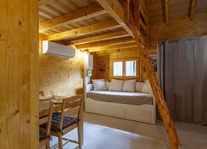 A cozy wooden cabin with a loft bedroom, a dining area, and a staircase.