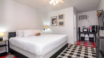 A bedroom with a bed, a nightstand, a lamp, a ceiling fan, and a checkered floor.