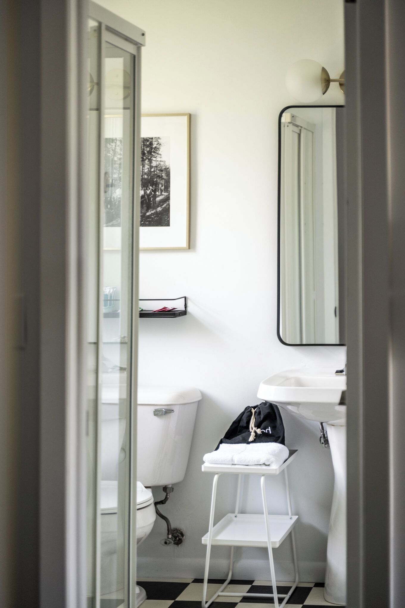 A small bathroom with a toilet, a sink, a mirror, and a framed picture on the wall.