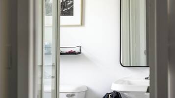 A small bathroom with a toilet, a sink, a mirror, and a framed picture on the wall.