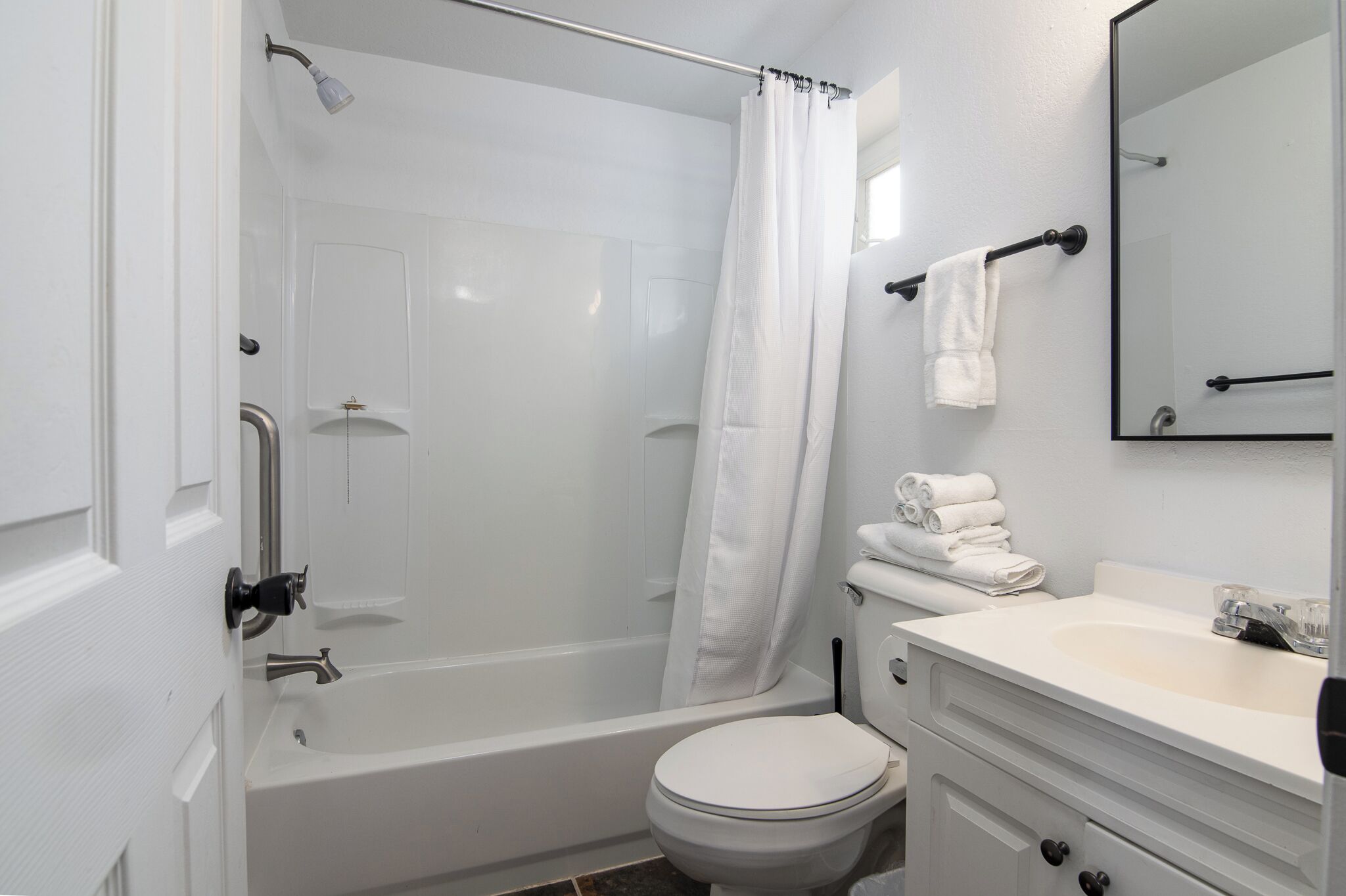 A bathroom with a bathtub, toilet, sink, and a mirror.