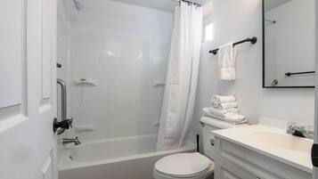 A bathroom with a bathtub, toilet, sink, and a mirror.