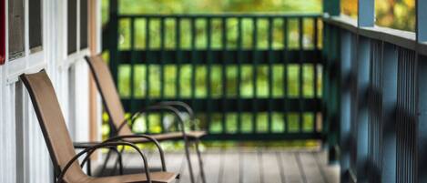 A porch with chairs and a railing.