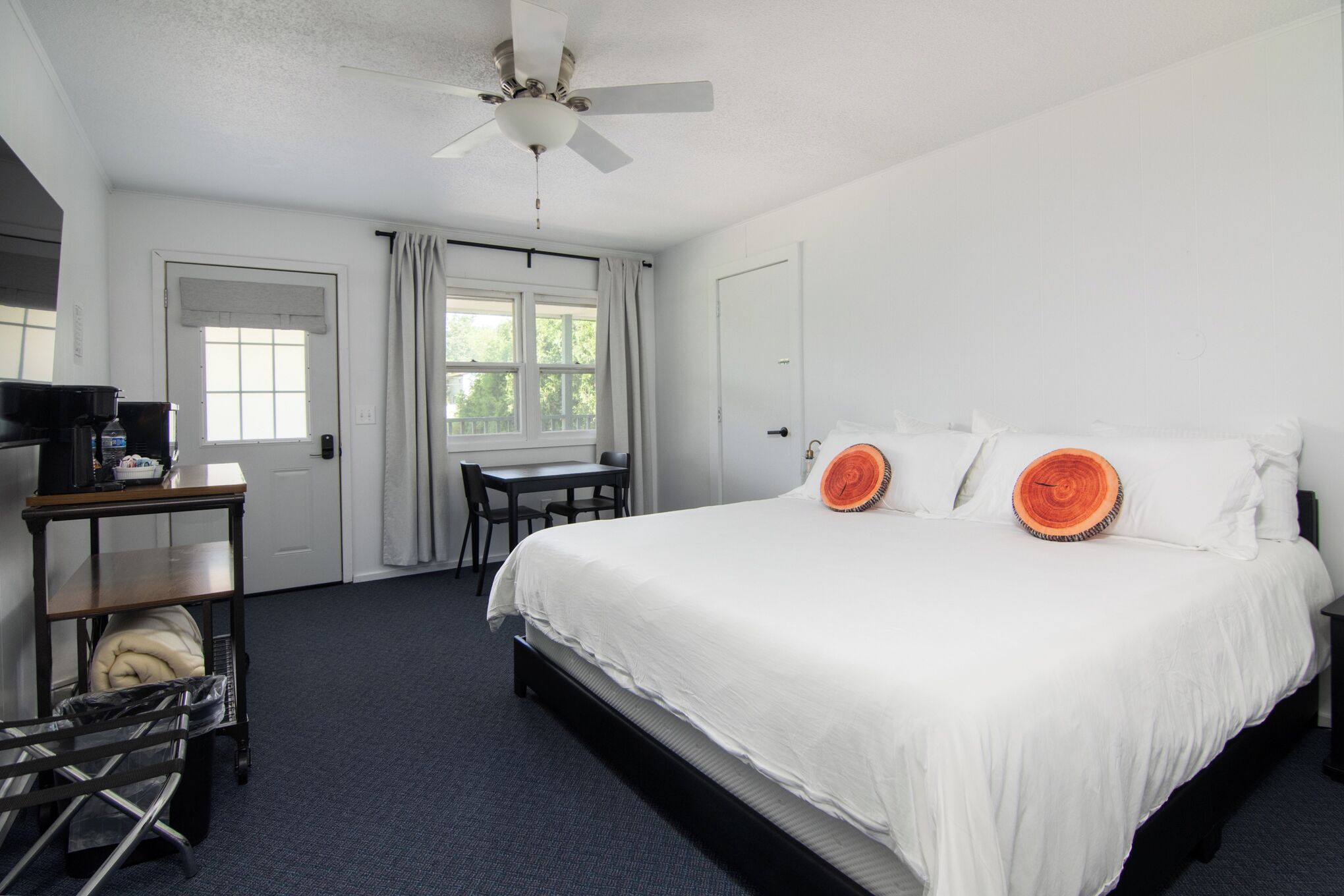 A hotel room with a bed, a desk, a chair, a ceiling fan, and a window.
