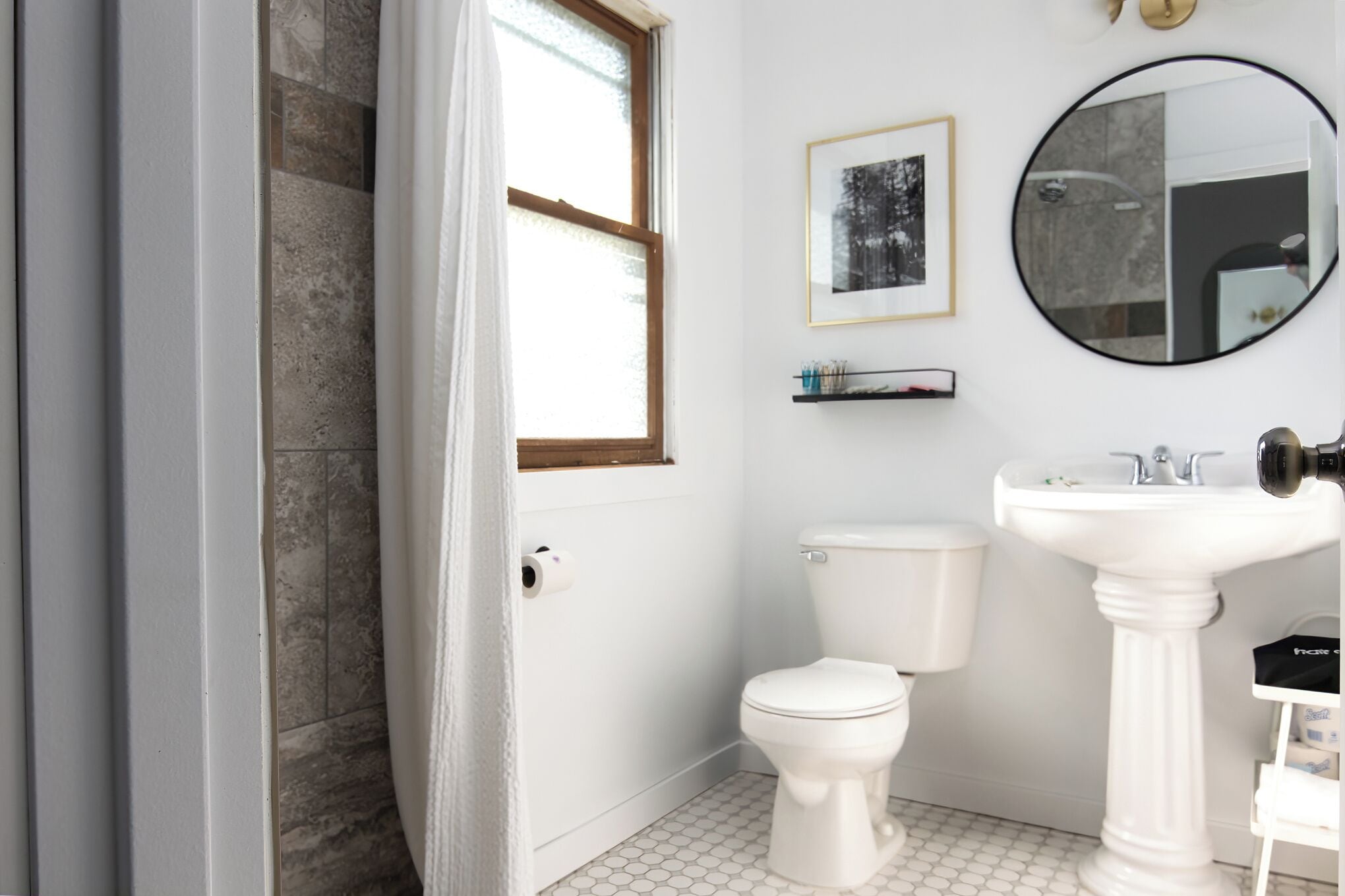 A bathroom with a toilet, sink, mirror, and a framed picture on the wall.