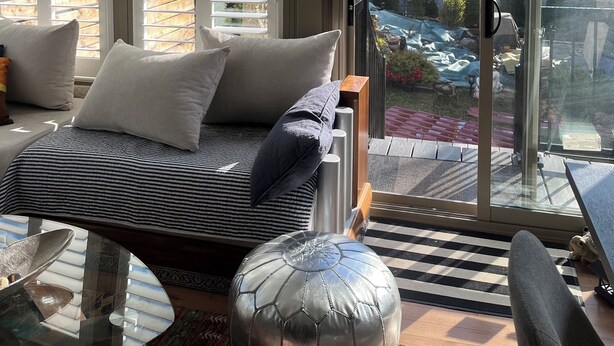 Een moderne kamer met een bed, een glazen deur naar een tuin en uitzicht op buiten.