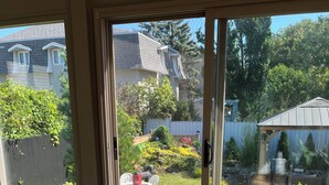 Een kamer met een schuifdeur naar een tuin, een kleine Boeddhabeeld, een houten stoel en een gestreept kleed.