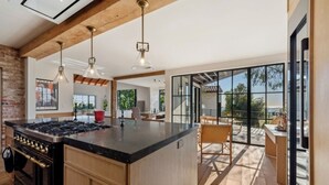 Een moderne keuken met een groot eiland, houten kastjes en hanglampen.