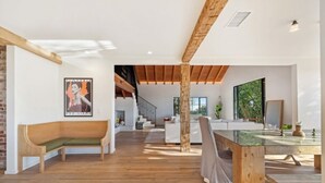 Een ruime woonkamer met een houten bank, een glazen salontafel en een trap naar een hoger niveau.