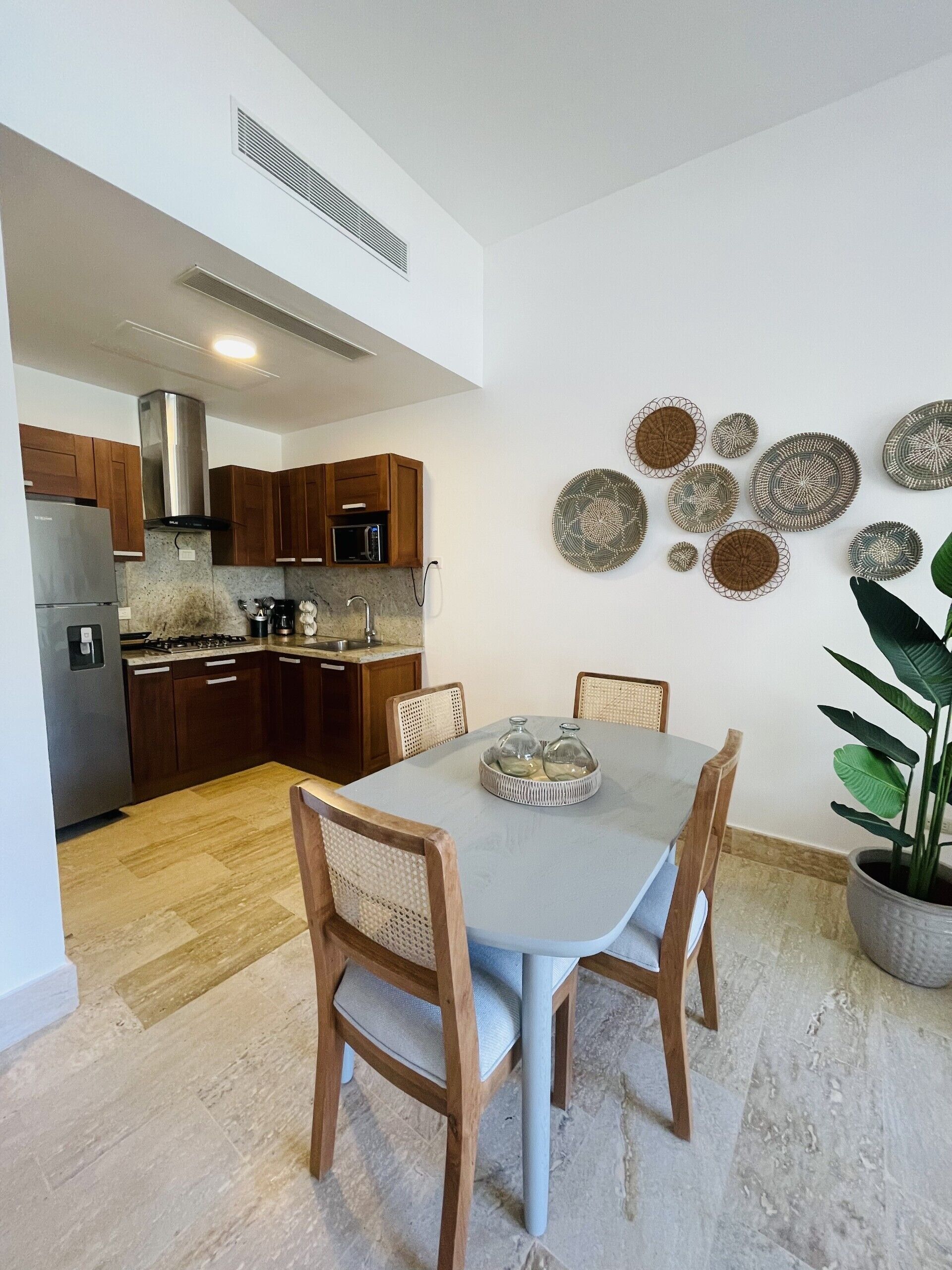 Una cocina moderna con armarios de madera, un refrigerador de acero inoxidable y un comedor con mesa y sillas.