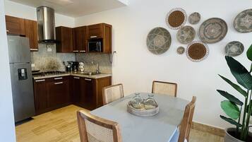 Una cocina moderna con armarios de madera, un refrigerador de acero inoxidable y un comedor con mesa y sillas.