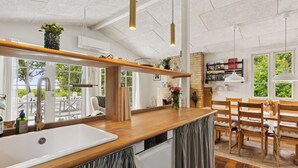 Een keuken met een houten aanrecht, een witte spoelbak en hangende lampen.