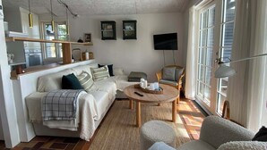 Een woonkamer met een bank, fauteuil, salontafel en een televisie.
