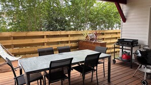 A covered patio with a table and chairs, a grill, and a wooden fence. - Family home, Seignosse bourg (Seignosse)