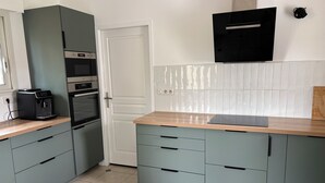 A kitchen with a built-in espresso machine, a microwave, and a stove. There is a white door and a tiled backsplash. - Family home, Seignosse bourg (Seignosse)